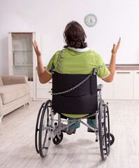 Young male invalid in wheel-chair suffering at home