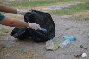 Cleanup volunteers woman picking leaves and plastic bottles into trash garbage bags,the concept of a clean natural environment