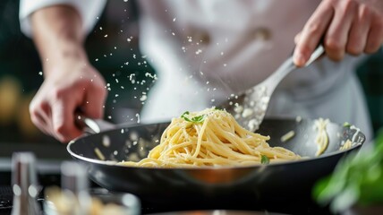 A chef skillfully flipping pasta in a saute pan in a modern kitchen - obrazy, fototapety, plakaty
