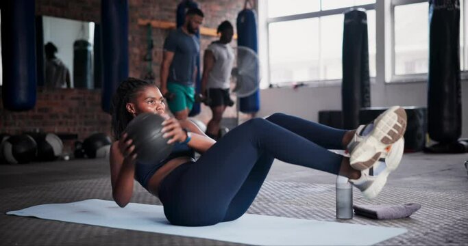 Black woman, medicine ball and workout on floor for exercise, training or fitness at gym. African female person in crunches for muscle, strength or endurance in practice for stamina at health club