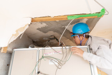 リフォーム工事　天井の電気配線を確認する作業員
