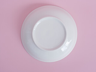 upside down white plate on pink background. Minimal style. Top view.