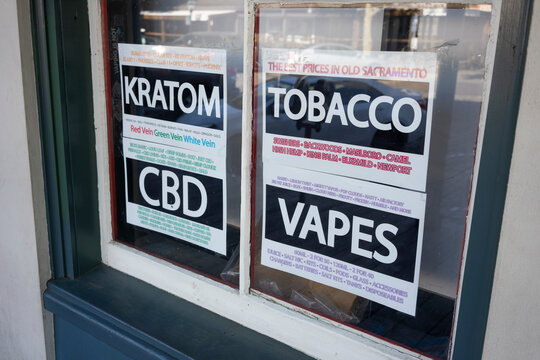 Sacramento, CA, USA - Mar 20, 2022: Kratom, CBD, Tobacco, and Vapes signs are seen on the storefront window at a tobacco shop in Sacramento, California.