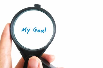 Hand holding magnifying glass focus on the text written MY GOAL. Concept of focusing on what matter...