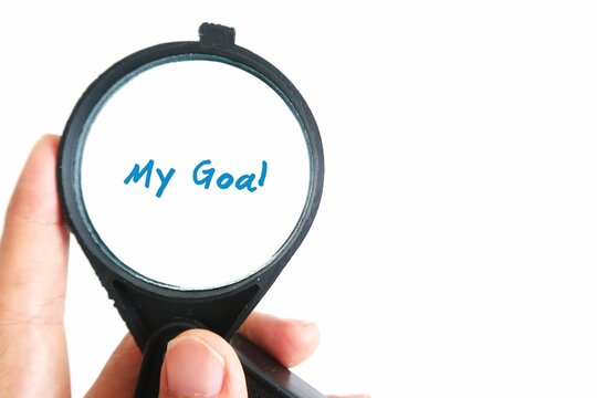 Hand holding magnifying glass focus on the text written MY GOAL. Concept of focusing on what matter most, goal in life.