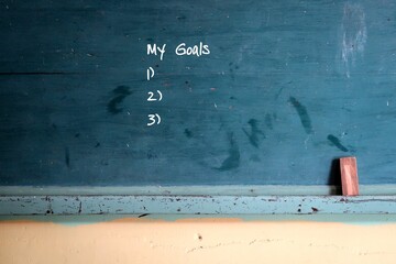 Green vintage school green chalkboard background with hand written text MY GOALS and blank lists.
