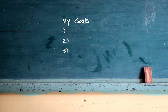 Green vintage school green chalkboard background with hand written text MY GOALS and blank lists.