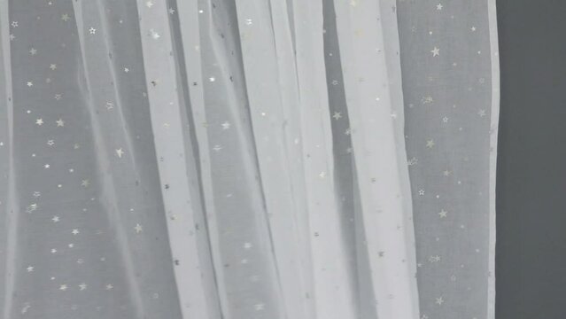 White tulle curtain is in motion. The fabric is delicate and thin cloth airy.