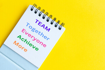 Team representing together, everyone achieve more. Team word on notepad on yellow background
