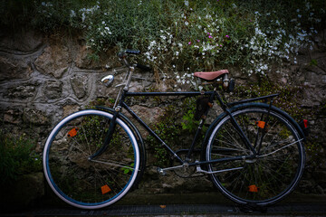 A vintage or retro,old black bike or bicycle with a brown seat,against a stone wall,Hallstatt,Austria - Powered by Adobe