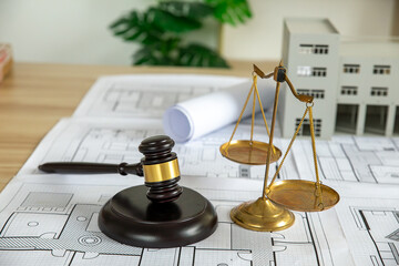 Wooden gavel, house and yellow helmet