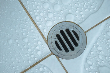 water drainage hole stainless, water stain wet floor on white tile background. System plumbing and environment concept.