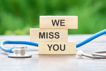 WE MISS YOU text on wooden blocks on a green background