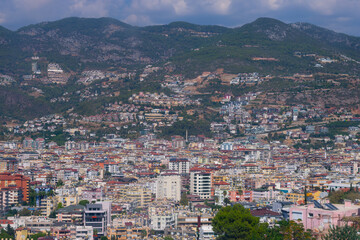 Fototapeta premium Top high angle view on little tiny houses with orange tiled roofs and green trees, mountains on bright summer sun.