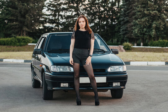 Sexy girl in short shorts and tights with high heels. pretty girl and car. stylish young beautiful girl