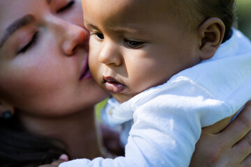 Mothers kissed baby. Close up portrait of mother kissing multiracial baby. Mother kiss child,...
