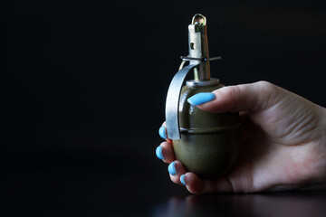 A woman's hand with a blue manicure holds a hand grenade. Concept of women's service in the Israeli...