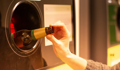Woman puts bottle in automatic bottle recycling machine. Reverse vending recycling machine.