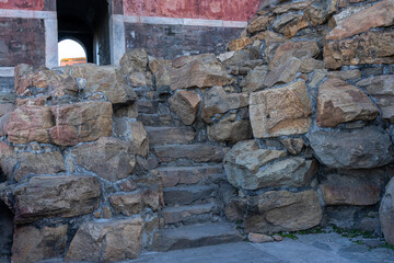 A hidden stone stairway between two permanently stacked raw hard rocks that lead to the entrance of a guard tower of an ancient palace in China.