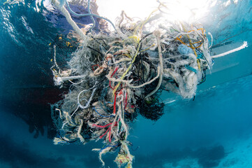 Abandoned debris fishing net or ghost net and plastic garbages in the sea. Clean up the ocean by...