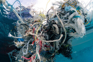 Abandoned debris fishing net or ghost net and plastic garbages in the sea. Clean up the ocean by collecting waste. Save the ocean and underwater world from trash pollution. Environmental conservation - 727666684