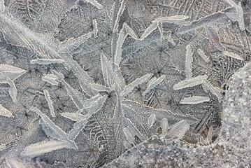 Ice crystals formed on the surface of the frozen puddle in winter.