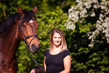 Fototapeta premium Young brunette woman in head portrait next to her horse. Sharp main subject.