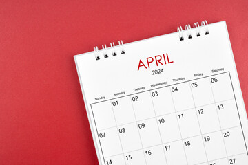 April 2024 desk calendar on red background.