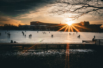 People walking over frozen lake at sunset
