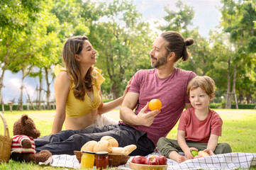 Fototapeta premium Happy family spending time on holiday. mother, father and little son having picnic in nature on a summer day. Leisure, summer, childhood concept.