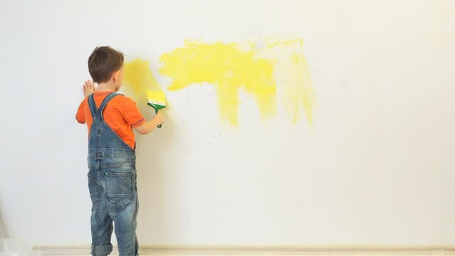 Kid painting with yellow the white wall of his room