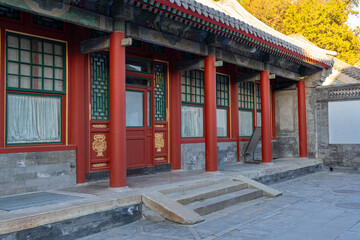 A typical traditional upper class Chinese house with common red entrance doors, red pillars, and stone staircase at the front on a sunny afternoon.