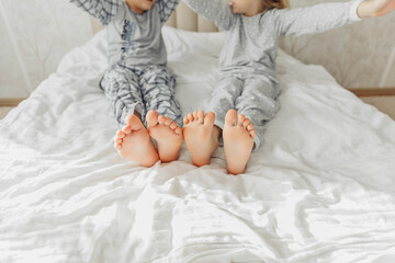 Obraz na płótnie Canvas the bare, clean feet of two children, offspring, lying side by side under the same blanket on the bed. morning relaxation, cozy rest. cute pictures of baby feet
