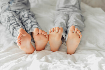 the bare, clean feet of two children, offspring, lying side by side under the same blanket on the...