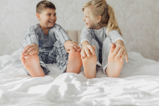the bare, clean feet of two children, offspring, lying side by side under the same blanket on the bed. morning relaxation, cozy rest. cute pictures of baby feet