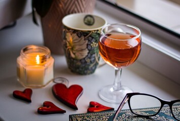 Still life with a candle, a mug and a glass of wine on a window sill