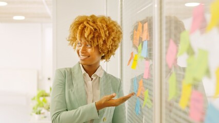 Woman pointing a post-it presenting ideas in a meeting