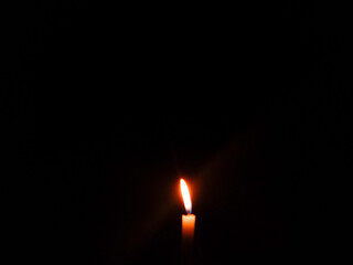 a candle is lit in the dark with a match. candle in the dark. candle flame burning in the dark....