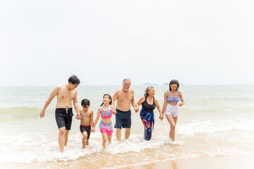 Group of Happy Multi-Generation Asian people family in swimwear enjoy and fun outdoor lifestyle travel nature ocean and playing in the sea together at tropical island beach on summer holiday vacation.