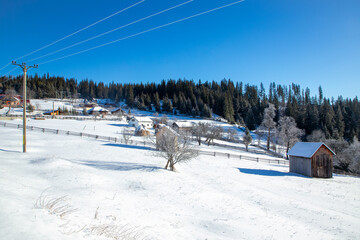 Landscape with traditional houses on the slope of a hill in Sadova village, Suceava county - Romania in winter