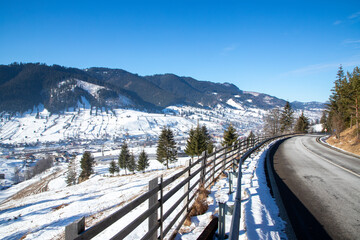 A beautiful landscape on a road in a rural mountain area in Romania in winter. A street in a village from Bucovina, Moldavia