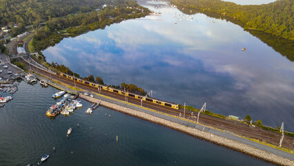 Aerial drone view of Hawkesbury River at Brooklyn, NSW Australia showing a train crossing...