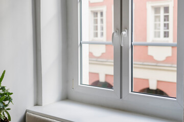 Close up of empty windowsill and plastic windows with white frames overlooking view on building