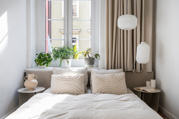 Scandinavian interior in bedroom with comfort double bed, blanket and pillows