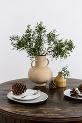 Table serving with plate, fork, pine cone decor and plant in ceramic vase