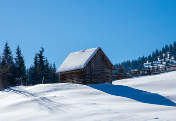 Landscape with an old wooden hut covered with snow in the mountain area