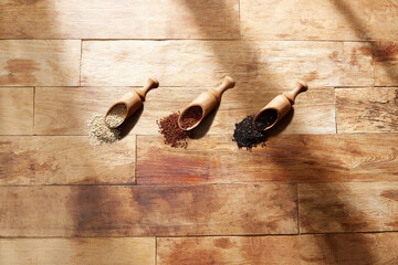 Wooden spoon, white quinoa, brown quinoa, black quinoa on wooden background