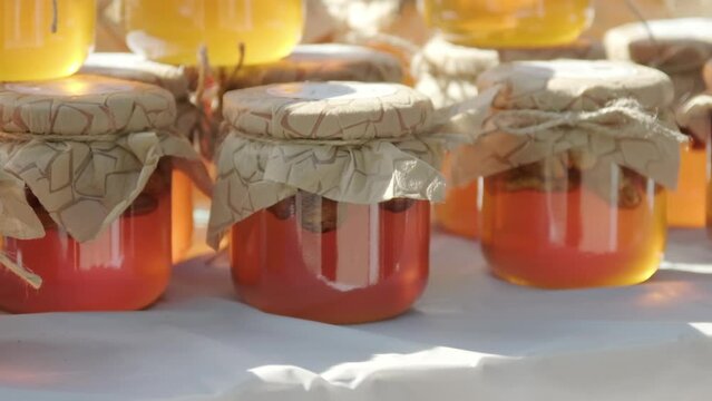 Rows of jars of bright yellow orange honey at the outdoor market