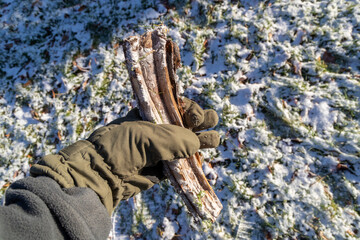 Ein Stück Holz im Winter mit Handschuhe aufheben.