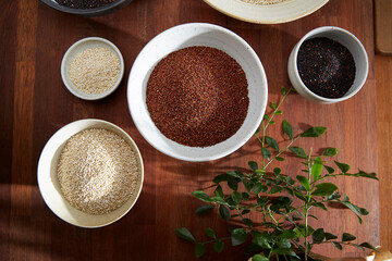 white quinoa, brown quinoa and black quinoa in ceramic bowl on wooden background